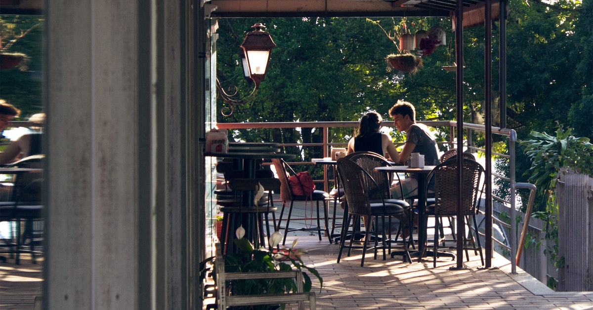 A man and woman sitting among tables and chairs outside the restaurant