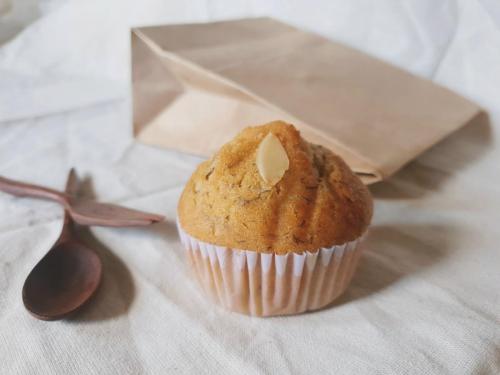 A muffin sitting in front of a brown bag